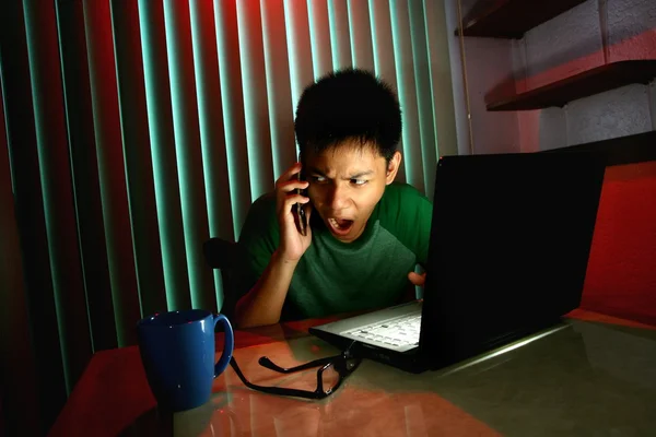 Adolescente joven usando un teléfono celular o teléfono inteligente frente a una computadora portátil —  Fotos de Stock