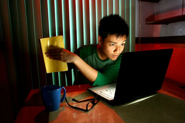 Joven adolescente sosteniendo un libro delante de un ordenador portátil —  Fotos de Stock