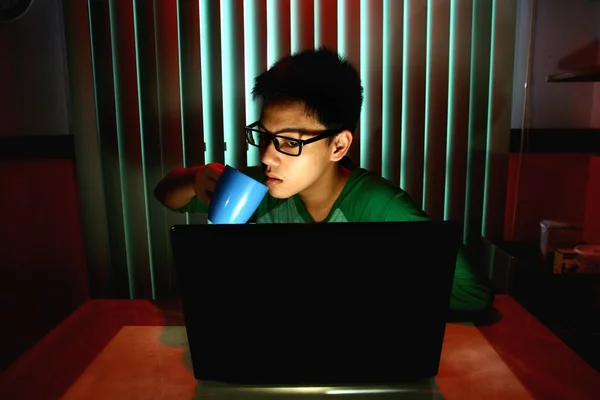 Junger Teenager trinkt Kaffee vor einem Laptop — Stockfoto