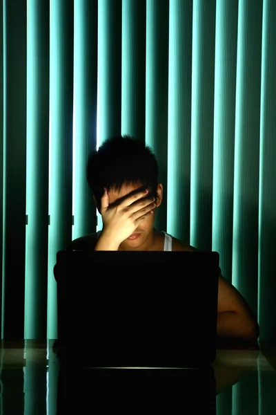 Young Teen in front of a laptop computer and covering his eyes — Stock Photo, Image