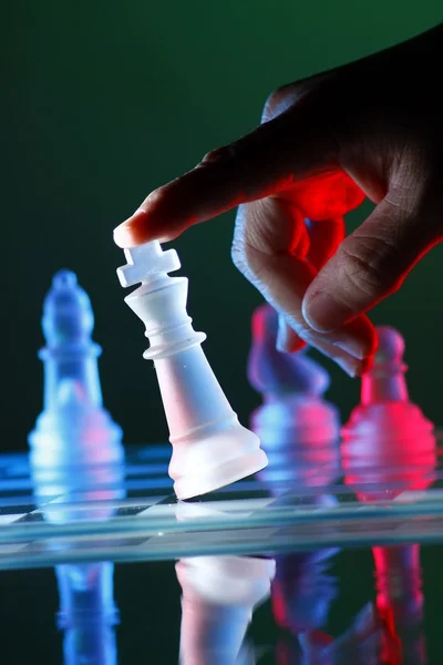 Palec przechylanie figurę szachową na szachownicy — Zdjęcie stockowe