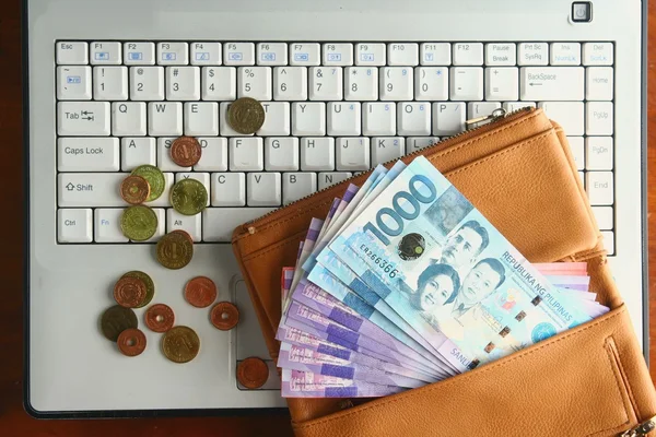 Bargeld in einer Ledertasche und Münzen auf einem Laptop — Stockfoto