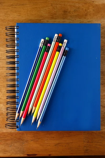 Colored Pencils and a notebook on a table — Stock Photo, Image