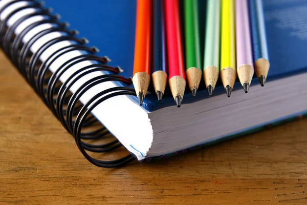 Colored Pencils and a notebook on a table — Stock Photo, Image