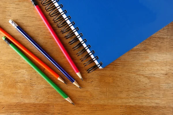 Buntstifte und Notizbuch auf einem Tisch — Stockfoto