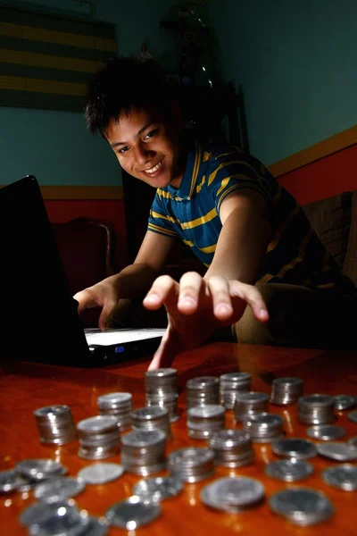 Asiatiska tonåringar framför bärbar dator och att nå för en stack av mynt — Stockfoto