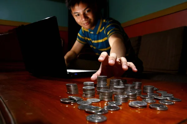 Asiatiska tonåringar framför bärbar dator och att nå för en stack av mynt — Stockfoto