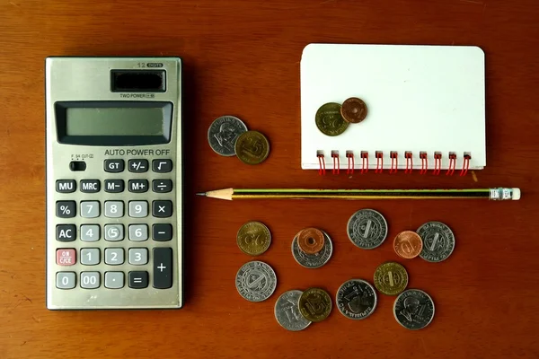 Moedas, calculadora, lápis e caderno — Fotografia de Stock