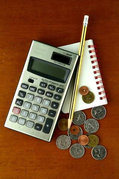 Munten, rekenmachine, potlood en notebook — Stockfoto