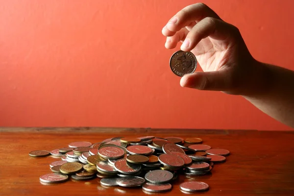 Elegir a mano una moneda de un montón de monedas sueltas — Foto de Stock