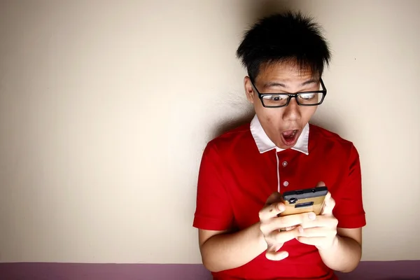 Nastoletni dzieciak korzystanie smartphone i stanowiąc zaskoczony — Zdjęcie stockowe