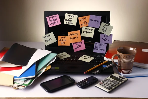 Ordenador portátil con mensajes en papeles de colores, teléfono celular, teléfono inteligente, portátil, bolígrafo, lápiz y anteojos — Foto de Stock