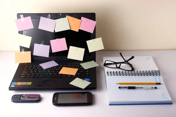 Ordenador portátil con papeles de colores, teléfono celular, smartphone, portátil, bolígrafo, lápiz y anteojos — Foto de Stock