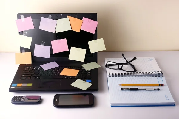 Laptop-Computer mit bunten Papieren, Handy, Smartphone, Notizbuch, Stift, Bleistift und Brille — Stockfoto