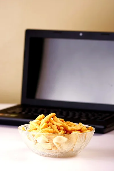 Mísa čipů nebo nezdravé potraviny a přenosného počítače na pozadí — Stock fotografie