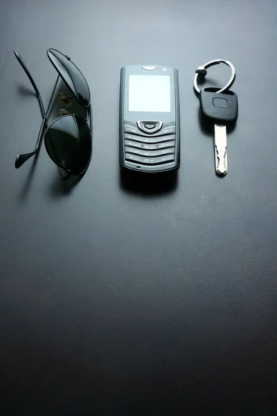 Gafas de sol, llave del coche y teléfono móvil en una mesa de madera —  Fotos de Stock