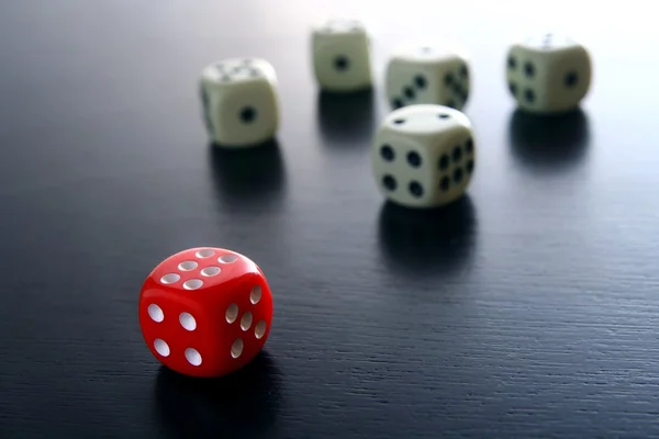 Ein roter Spielwürfel vor fünf weißen Spielwürfeln — Stockfoto
