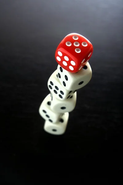 Ein roter Spielwürfel auf fünf übereinandergestapelte weiße Spielwürfel — Stockfoto