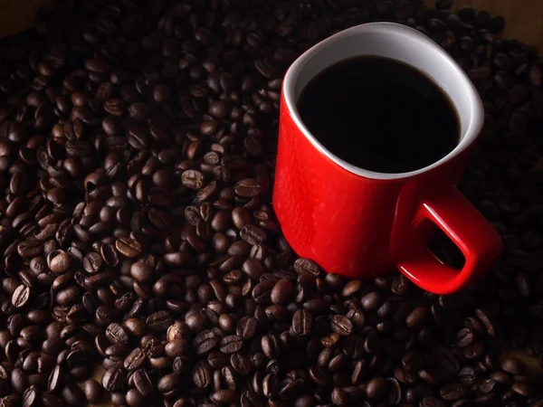 Kaffebönor och en röd kaffekopp — Stockfoto