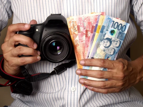 Man holding a camera and Philippine peso bills — Stock Photo, Image