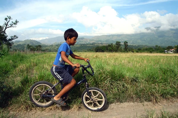 Un garçon fait du vélo le long d'une rizière — Photo