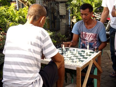 An old man sits on a sidewalk in Antipolo city