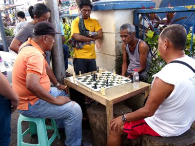 An old man sits on a sidewalk in Antipolo city