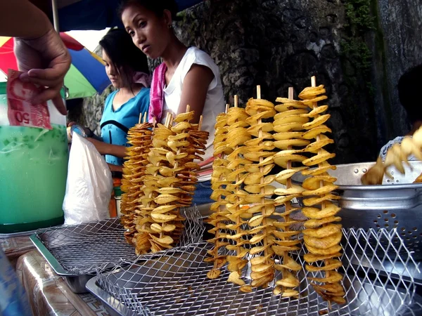 Street vendor sells fried potatoes on a stick — Stok fotoğraf