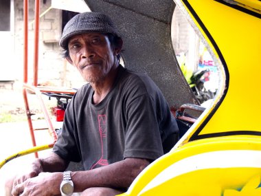A tricycle driver rests in the cab of his tricycle while waiting for passengers.