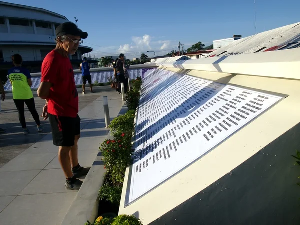 Un uomo legge i nomi in un monumento in ricordo di coloro che sono morti nell'ondata di tempesta causata dal tifone Yolanda. — Foto Stock