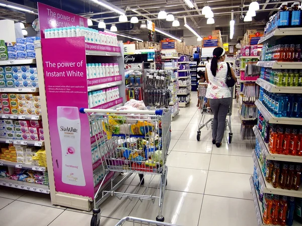 Un cliente pasa por delante de productos orales y para el cuidado del cuerpo en los estantes de una tienda de comestibles — Foto de Stock