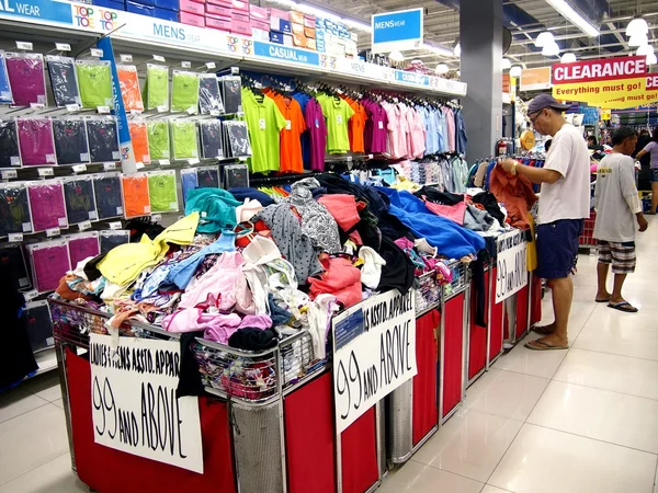 Bir müşteri bir bakkal renkli elbise yığını geçer