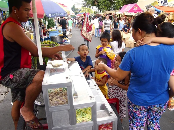 Děti koupit bonbony a cukrovinky od pouličního prodavače — Stock fotografie