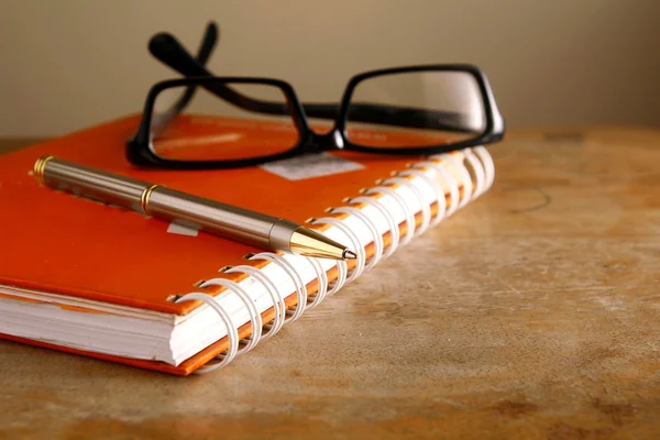 Gafas graduadas, cuaderno y un bolígrafo — Foto de Stock