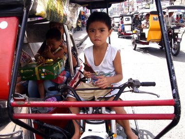 Bir çocuk bir üç tekerlekli bisiklet sürücü koltuğunda oturur
