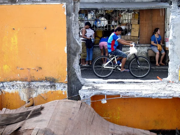 Customers at a store seen through the window of a demolished old building structure — Stock Photo, Image