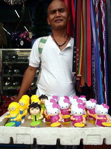 Un hombre vende diferentes tipos de juguetes en una acera — Foto de Stock