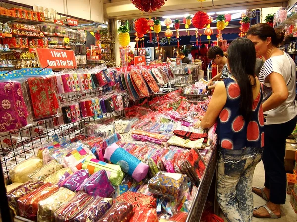 Os turistas escolhem entre uma variedade de produtos de lembrança em uma loja ou loja em Chinatown, Cingapura . — Fotografia de Stock