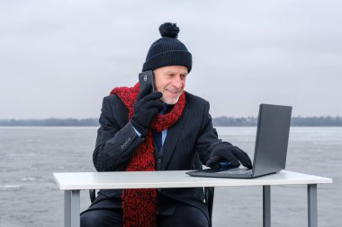 Yaşlı gri sakallı iş adamı, akıllı telefonla konuşurken gülümsüyor.