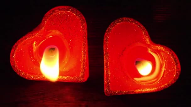 Couple de deux bougies en forme de cœur s'allumant ensemble sur une table en bois sombre — Video