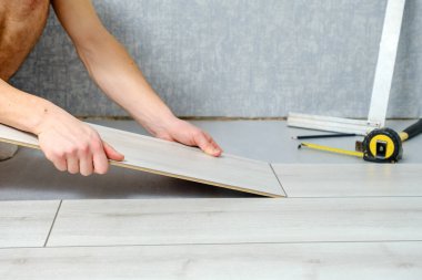 Erkek eller, ahşap kaplamalı zemin döşemesini kapalı mekanlara yerleştiriyor..