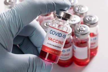 İnsan eliyle yapılan aşı şişesi ve bir sürü cam şişe. 