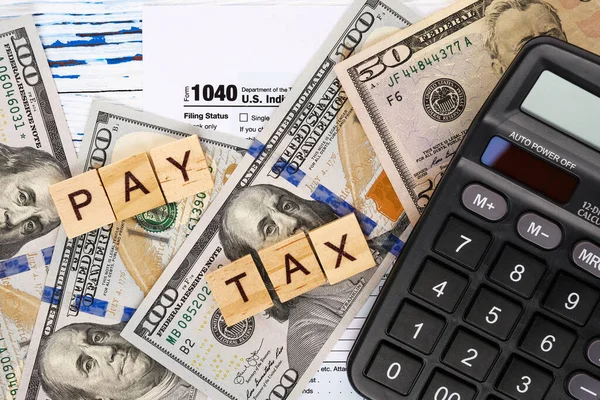 Words pay tax on form 1040, dollar bills and calculator. — Fotografia de Stock