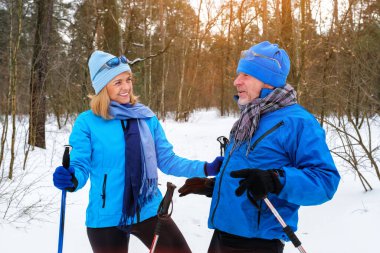Emekli yaşlı çift dinleniyor ve karlı kış parkında eğleniyor.