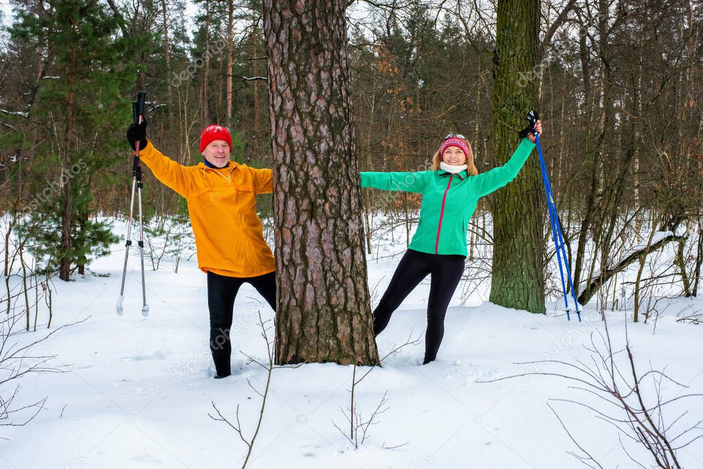 Senior couple walking with outstretched arms in snowy winter forest