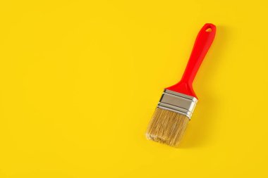 Sarı arka planda kırmızı saplı boya fırçası.