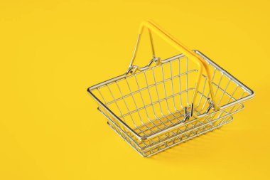 Sarı arka planda izole edilmiş metal tel alışveriş sepeti