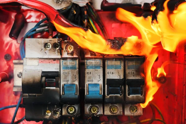 Burning switchboard from overload or short circuit on wall closeup