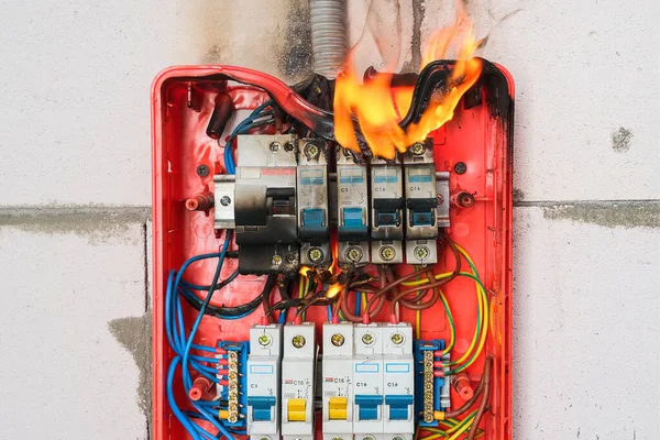 Burning switchboard from overload or short circuit on wall closeup