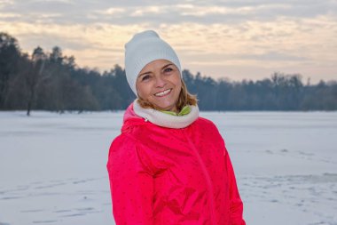 Yaşlı kadın kış ormanında duruyor, egzersizden sonra dinleniyor.